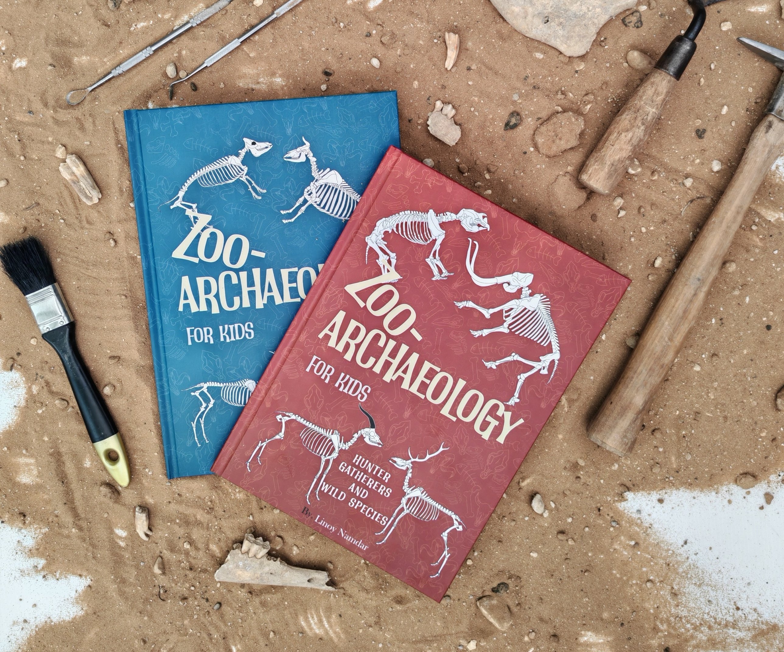 Both ZooArchaeology for Kids books laid on an excavation site with archaeology tools